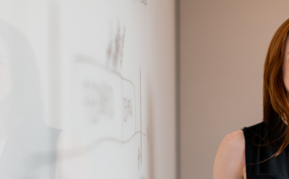 Red-haired lady standing in front of a whiteboard